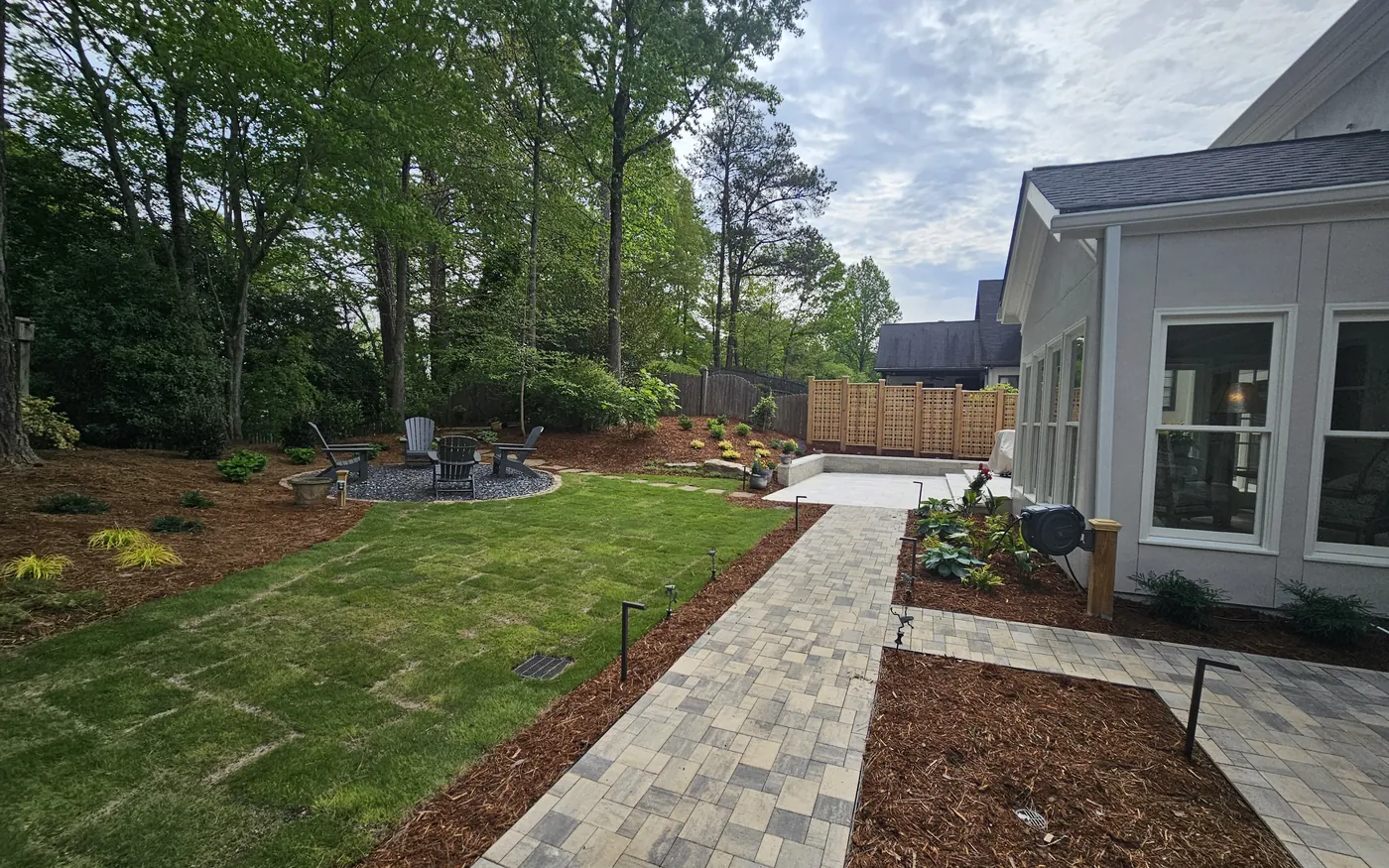 Same Alpharetta backyard after renovation, paver patio, fresh sod, and fire-pit lounge by 4 Seasons