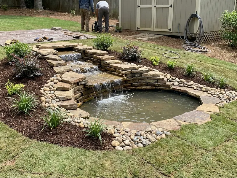 Waterfall flowing over stacked stone into a pond